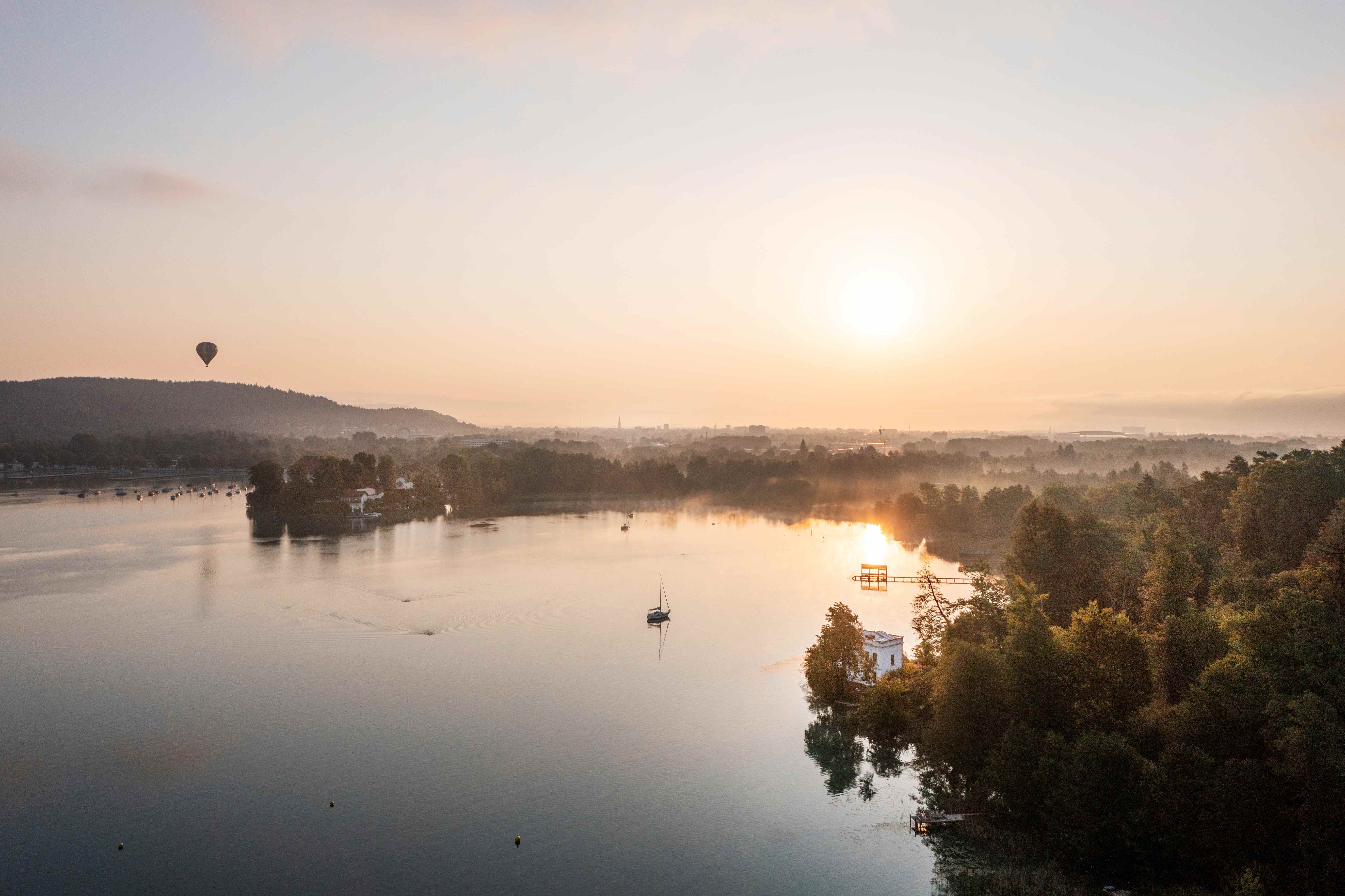 Drohnenshot vom Wörthersee Ostufer in Richtung Stadt bei Sonnenaufgang